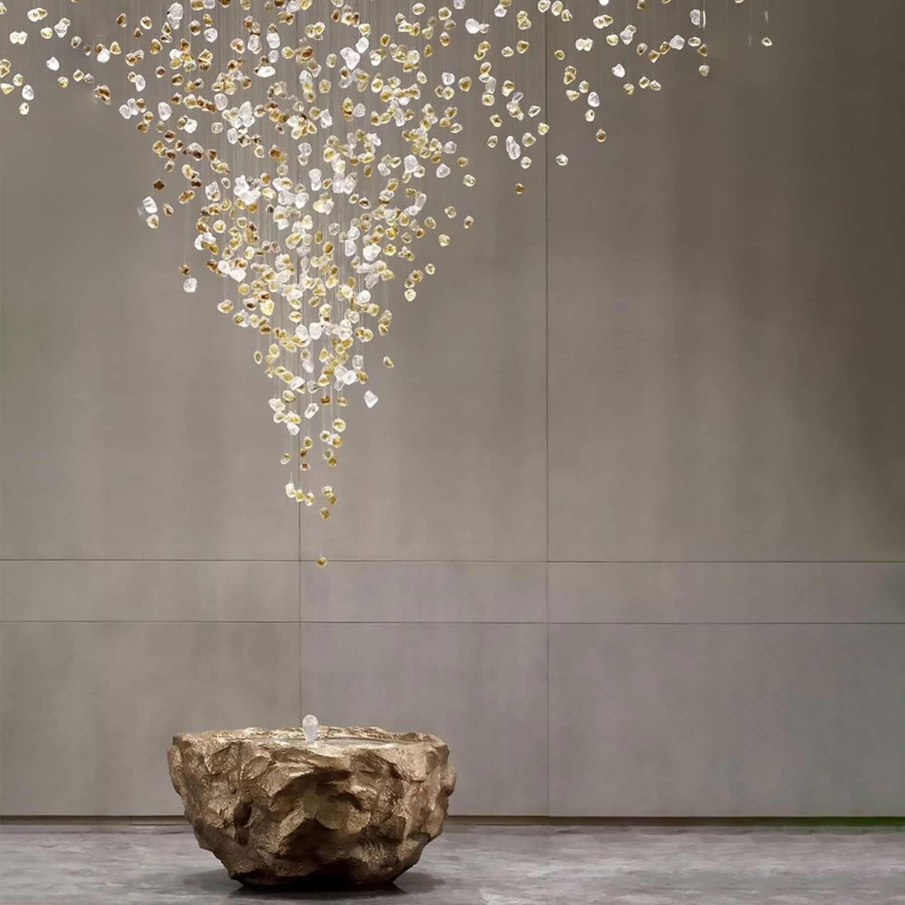 Cascading crystal chandelier above a textured bronze rock basin