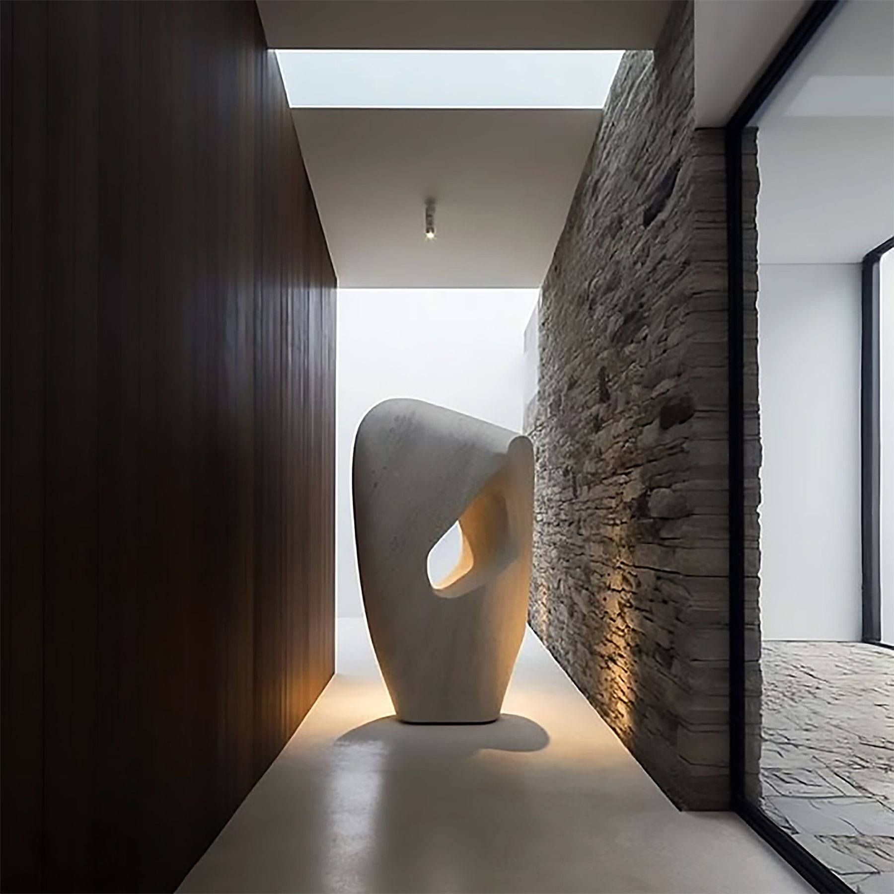 Hallway with organic stone sculpture, dark timber panelling and stacked stone wall