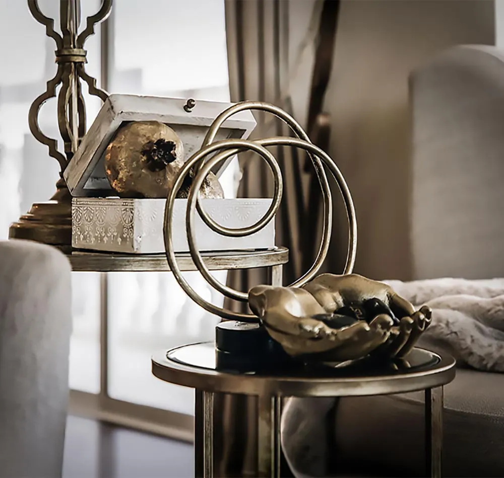 Gold side tables styled with sculptural objects and a white decorative box