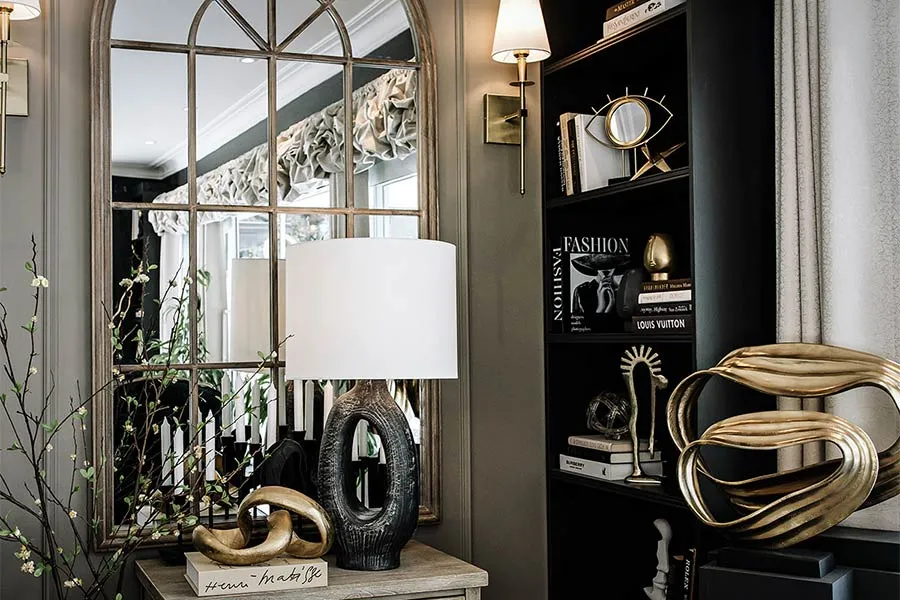 Console vignette with sculptural lamp, arched mirror and gold objects